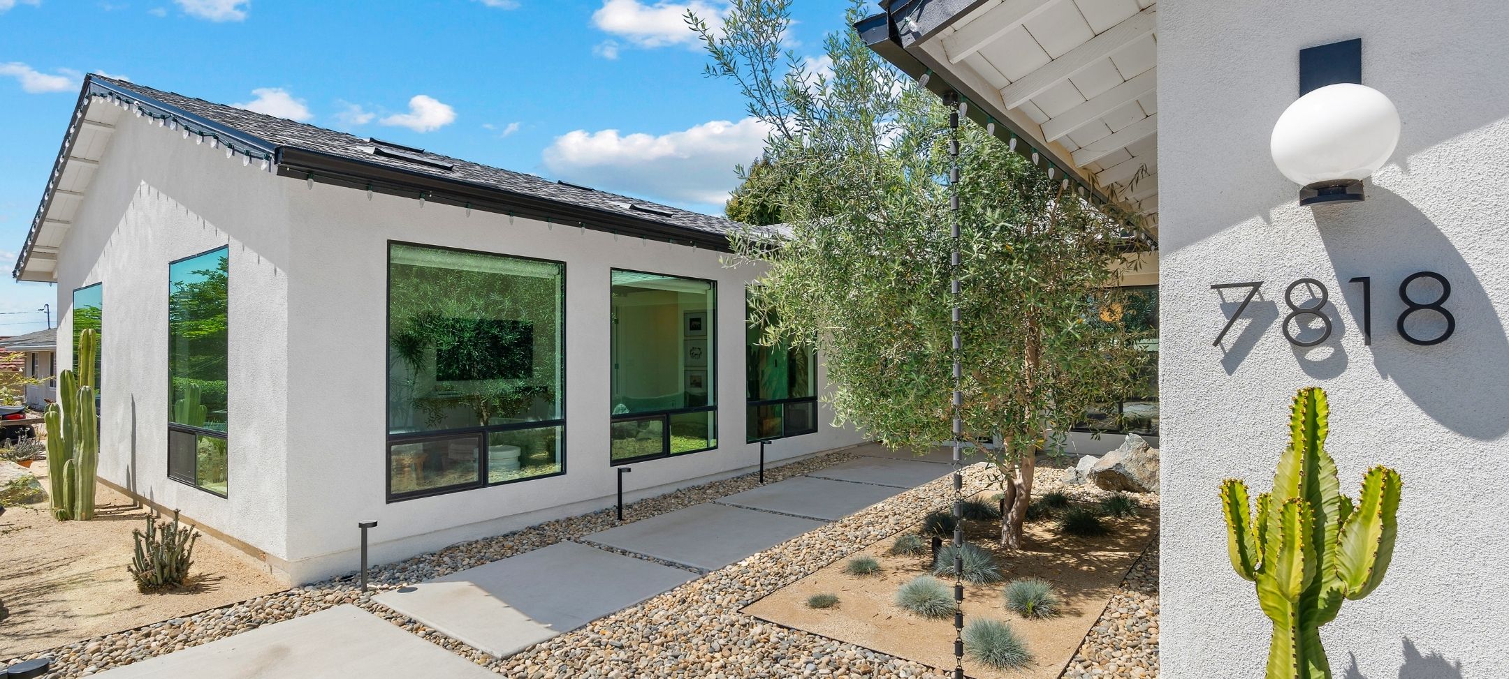 Modern desert-landscaped ADU exterior with white stucco, black-framed windows, and cactus garden