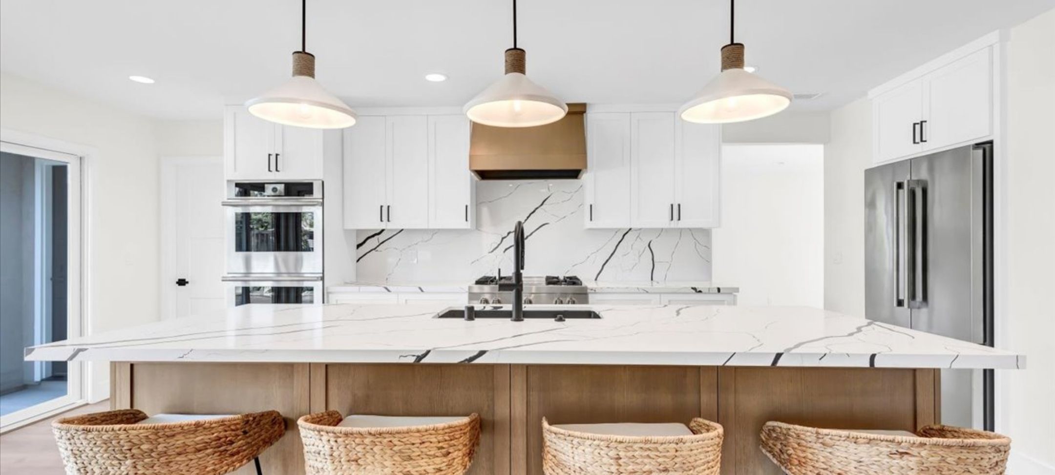 ADU kitchen remodel with white cabinetry, marble slab backsplash, and woven counter stools