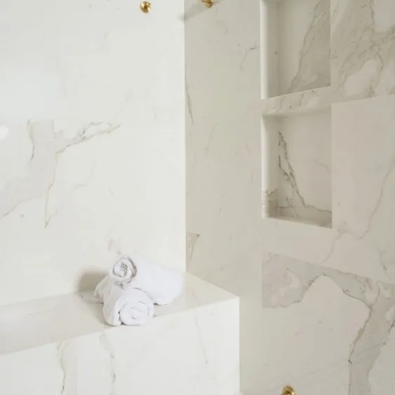 San Diego custom shower remodel with built-in bench seating, recessed niches, and white marble-look tile