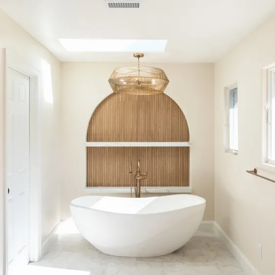 San Diego primary bathroom remodel with a freestanding soaking tub beneath a skylight and arched wood accent wall