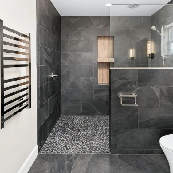 San Diego curbless walk-in shower remodel with charcoal tile, pebble flooring, frameless glass, and a built-in niche