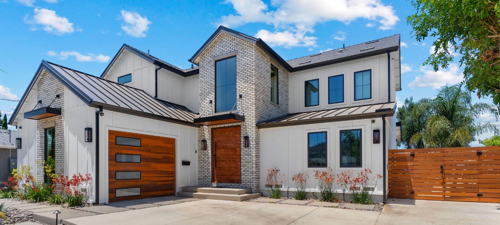 Two-story modern farmhouse exterior with white board-and-batten siding and wood front door, San Diego design-build new home