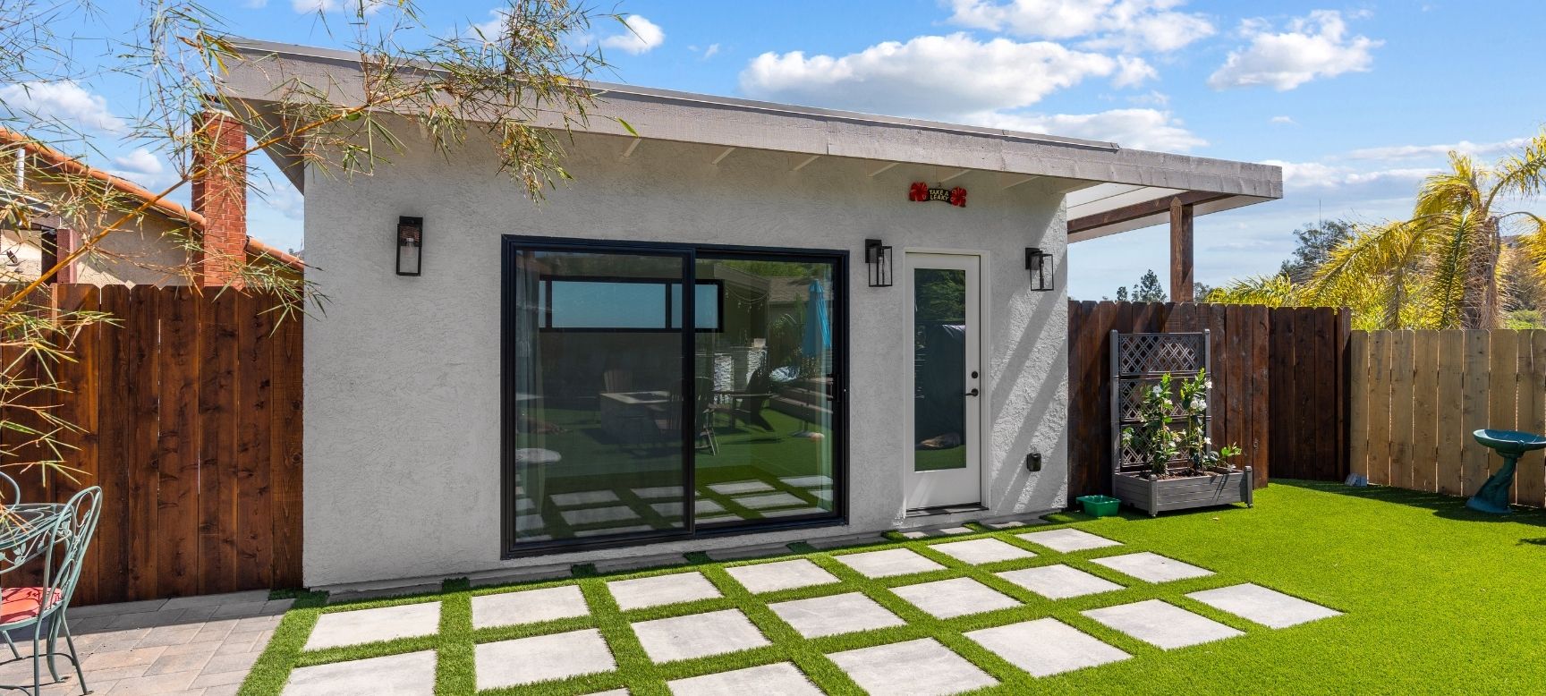 Backyard ADU studio exterior with sliding glass doors and turf yard, San Diego design-build project
