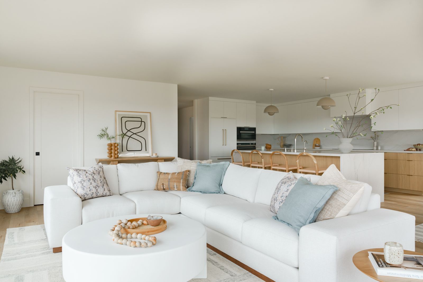 Completed Lars whole-home remodel with a white sectional, natural wood kitchen, and coordinated neutral finishes