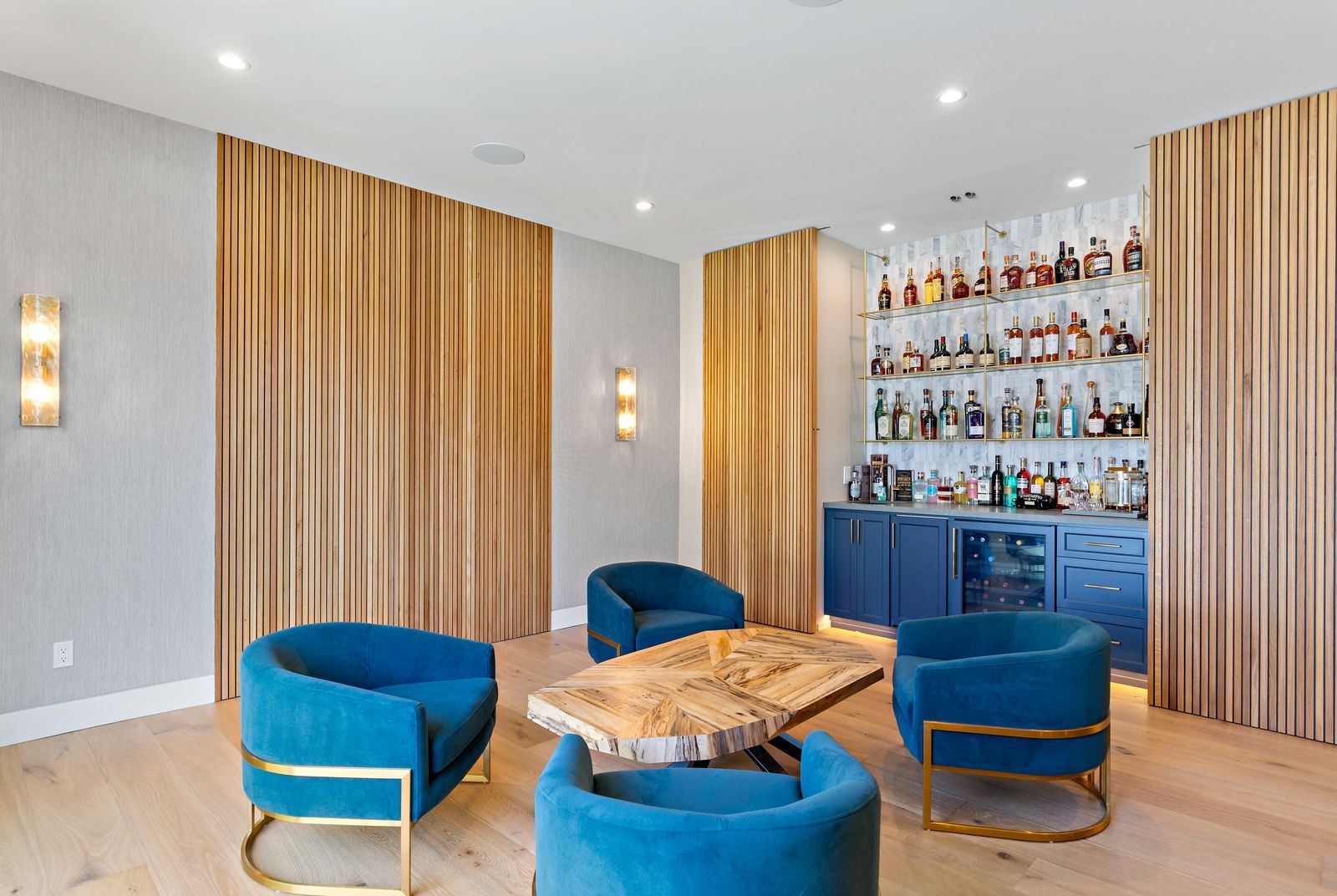 Completed Lars lounge with blue seating, vertical wood paneling, brass accents, and a built-in bar