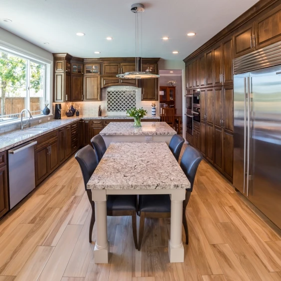 Galley kitchen remodel in San Diego with dark wood cabinetry, a central table, and hardwood flooring