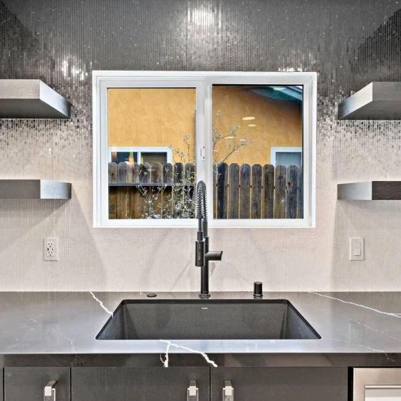 Black mosaic kitchen backsplash with stone countertop and sink in a San Diego remodel