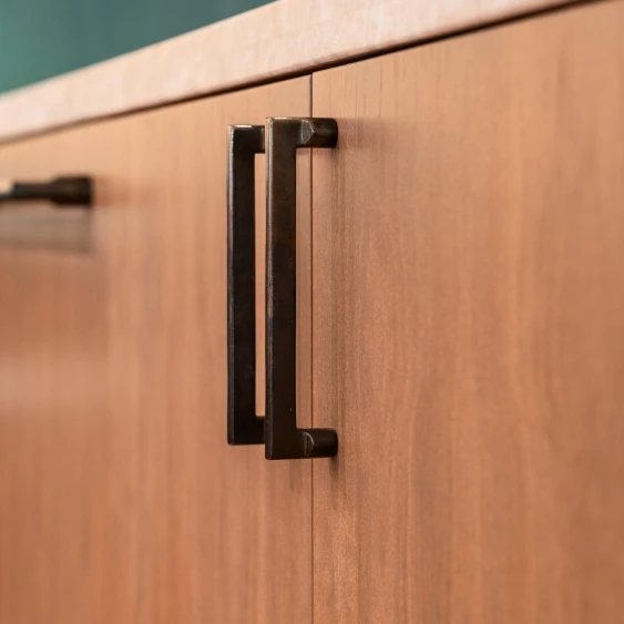 Matte black cabinet pull on warm wood cabinetry for a San Diego kitchen remodel