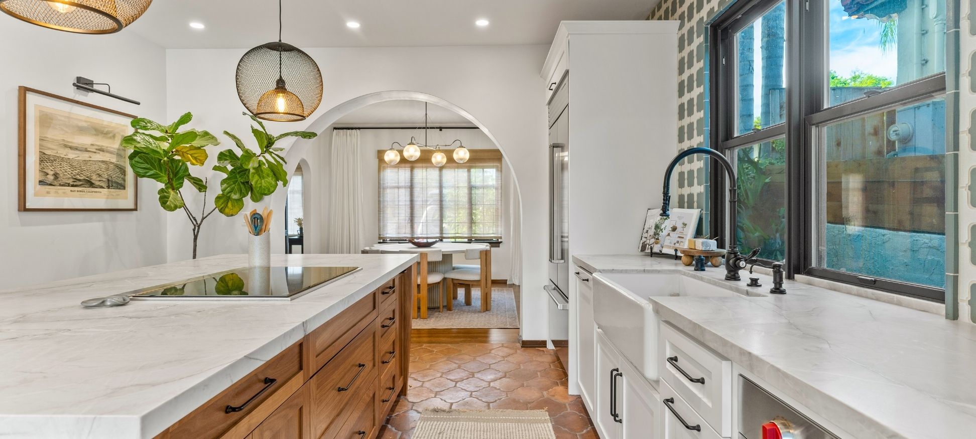 Spanish-style kitchen remodel with wood island, arched doorway to dining nook, and terracotta tile flooring