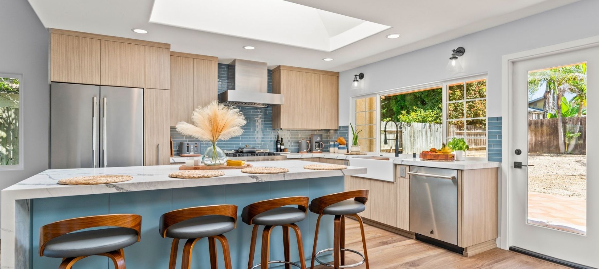Kitchen remodel with blue tile backsplash, two-toned wood cabinetry, skylight, and waterfall island seating