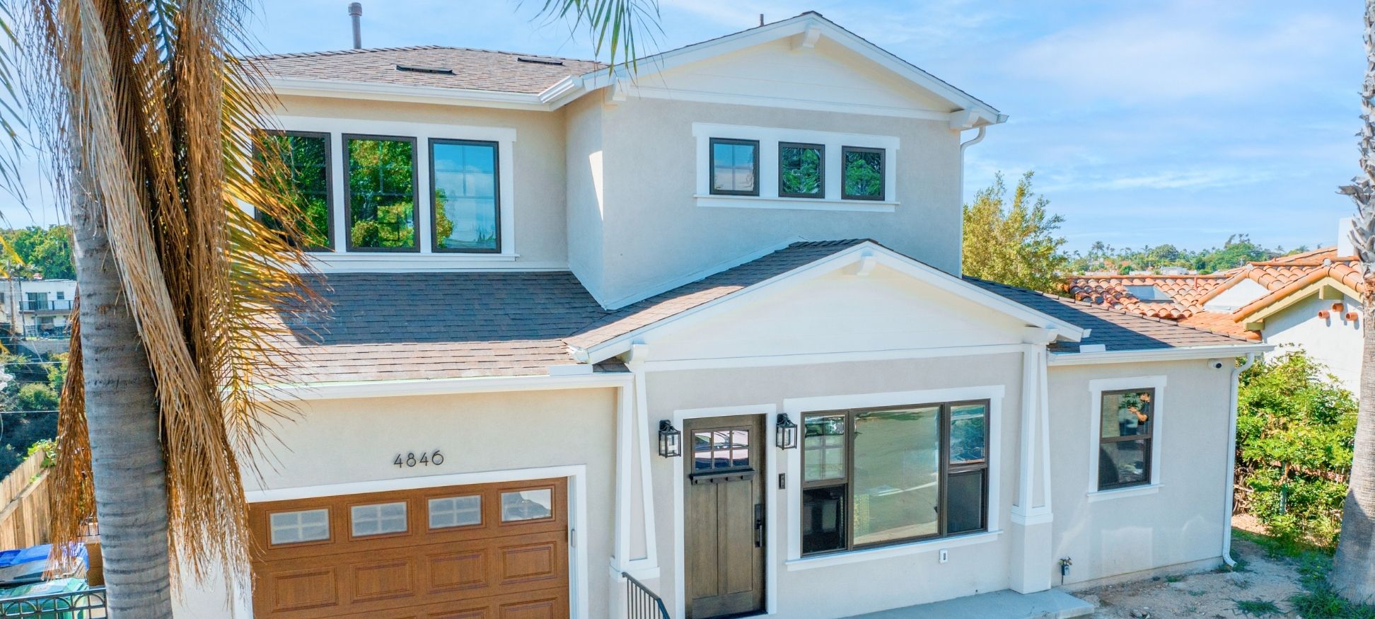 Two-story whole home remodel exterior with cream stucco, gable roofline, and craftsman wood entry door