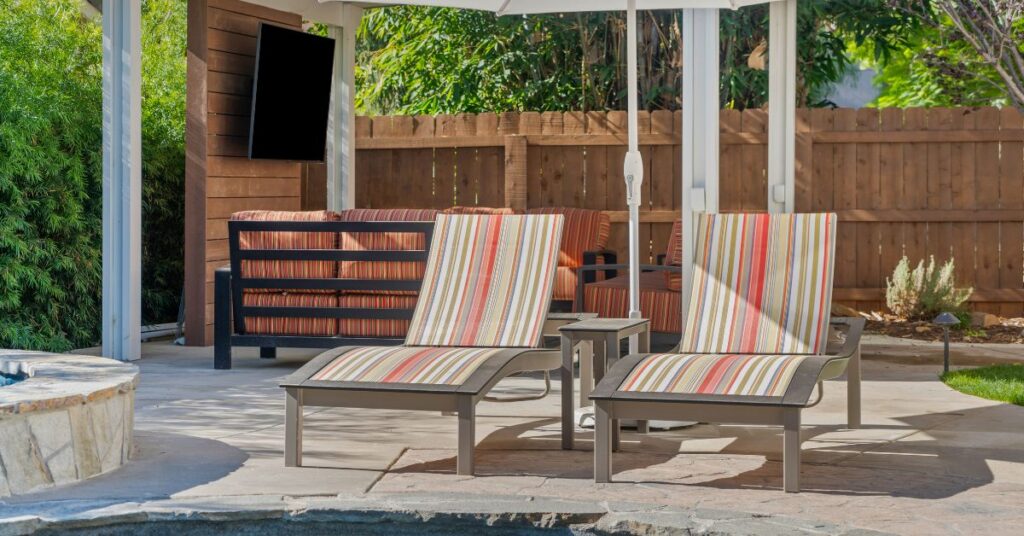 Sustainable outdoor living space with poolside lounge chairs, shaded patio seating, and low-maintenance landscaping, showcasing eco-friendly backyard design ideas for modern homes.
