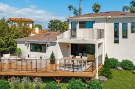 Custom backyard deck design with outdoor seating, dining space, and modern railings attached to a remodeled two-story home, showcasing functional and stylish deck remodeling ideas.