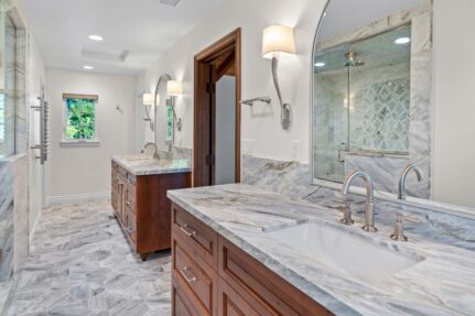 Primary bathroom remodel with dual sinks, custom cabinetry, a spacious walk-in shower, and elegant marble-look tile throughout.