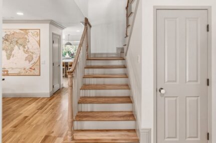 Remodeled home interior featuring a hardwood staircase, updated flooring, and an open-concept layout that improves flow between living spaces and supports a seamless home addition.