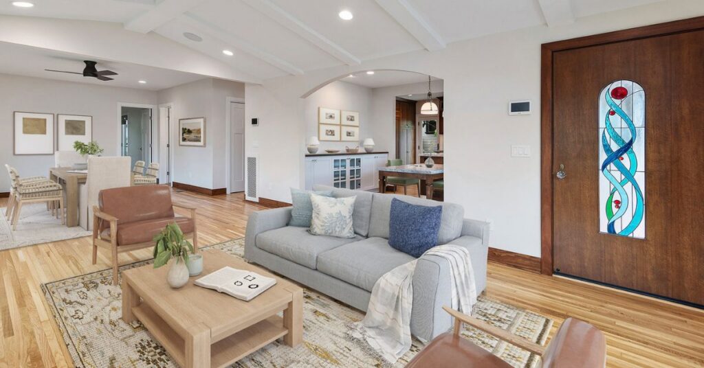Bright open-concept La Jolla living room with hardwood floors, custom wood entry door, comfortable seating, and seamless flow into dining and entertaining spaces, designed for both everyday living and hosting guests.