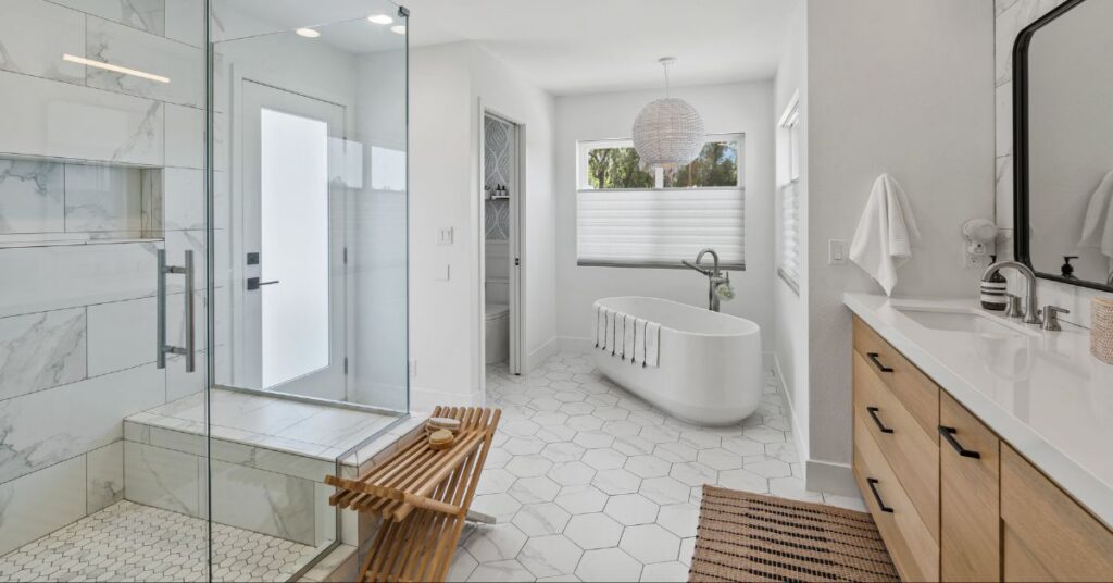 Spa-inspired luxury bathroom with a glass shower enclosure, freestanding bathtub, custom vanity, marble-look tile, and high-end modern finishes.