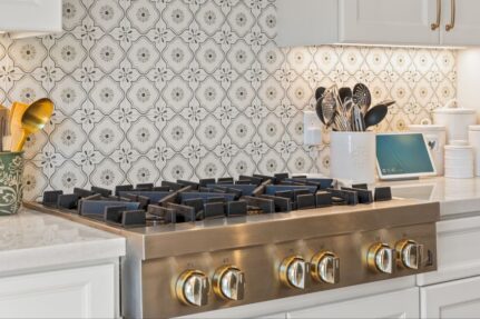 Luxury kitchen remodel with a stainless steel gas range, custom tile backsplash, white shaker cabinets, quartz countertops, and designer finishing touches.