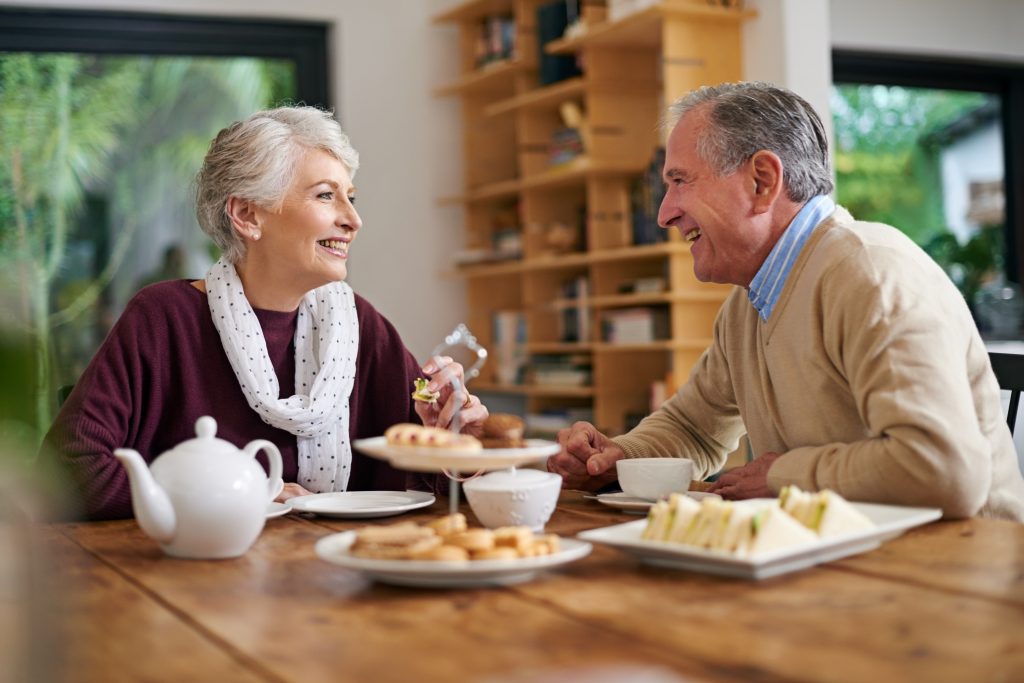 a happy senior couple is talking with each other on breakfast table