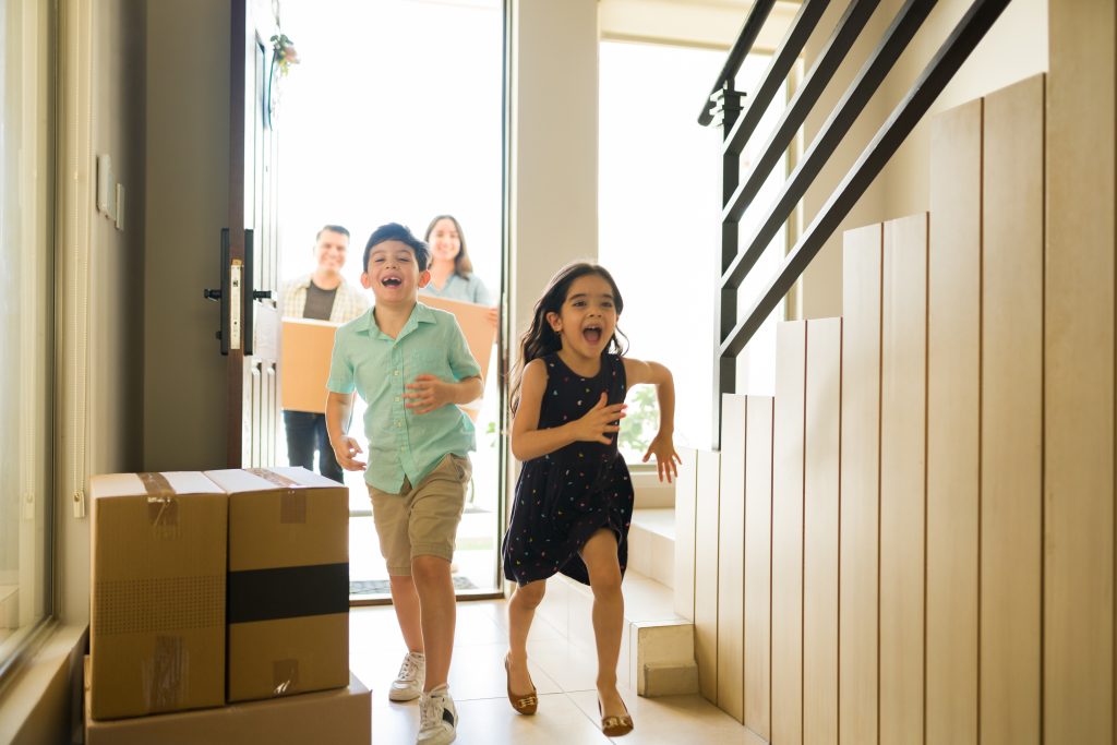 children laughing while entering new home with parents