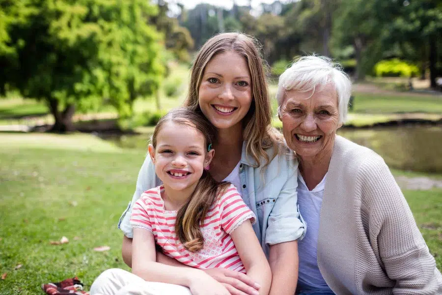A daughter, mom, and grandma posing in front of a lake.