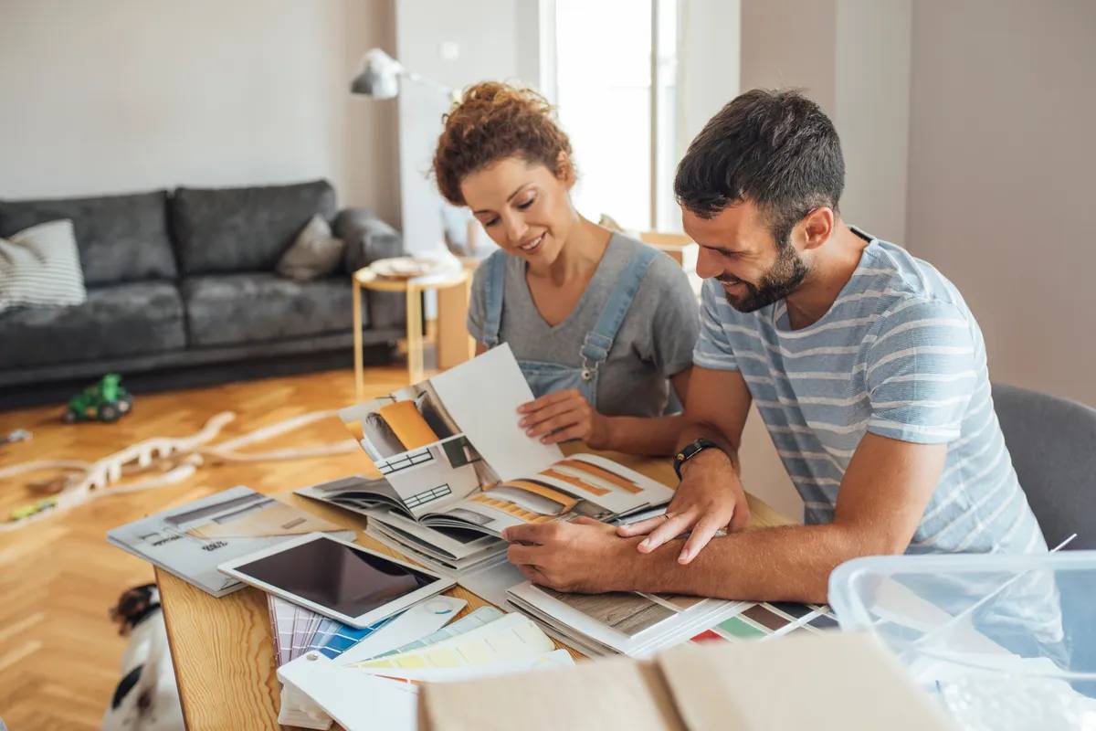 Couple sitting at a wooden table looking through design catalogs