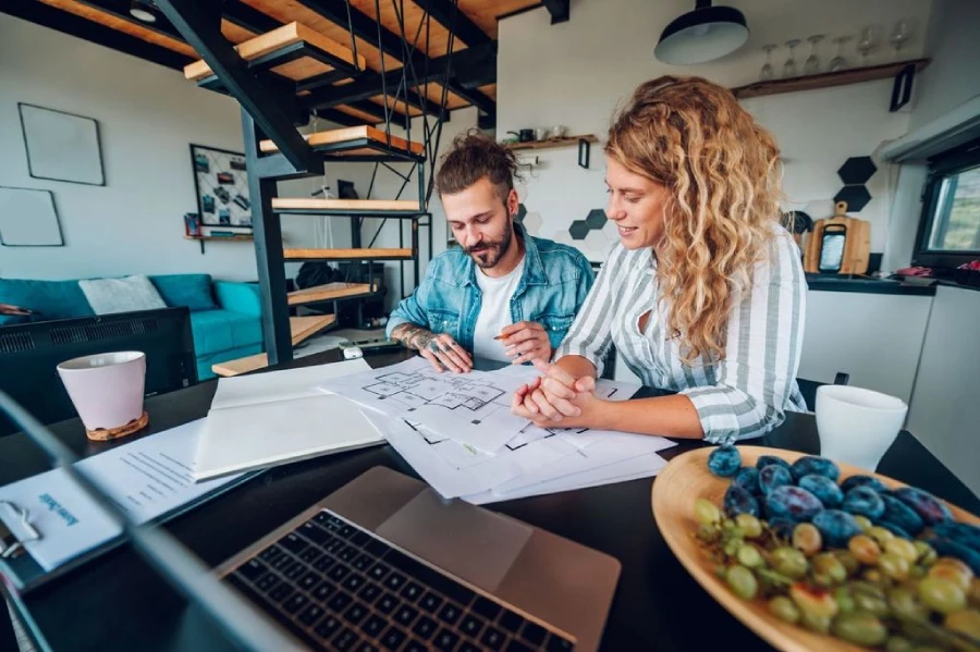 Husband and wife sitting at a dining room table designing their home.
