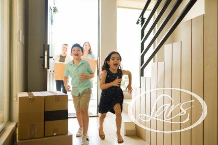children laughing while entering new home with parents