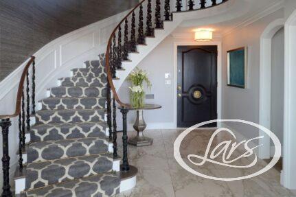 Bottom landing of a luxurious, carpeted staircase with marble flooring.