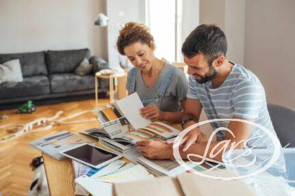 Couple sitting at a wooden table looking through design catalogs