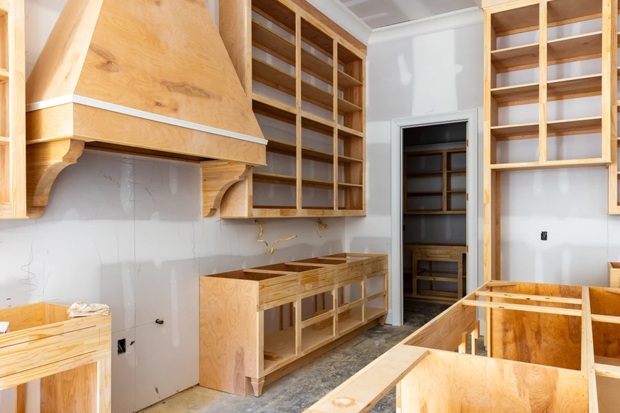 A kitchen remodel with the cupboards and oven vent being framed in.