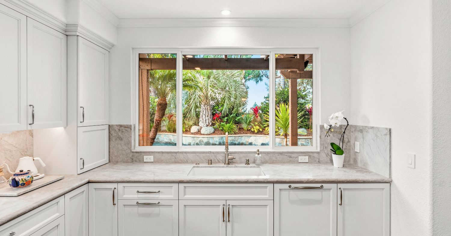 Carmel Valley kitchen remodel before and after — dark oak cabinets and honey granite replaced with white shaker cabinetry, navy island, and marble countertops, by Lars Remodeling & Design