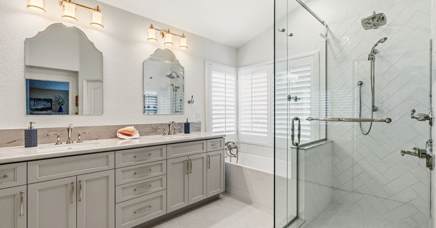 Carmel Valley primary bathroom remodel — double vanity with marble countertop, herringbone tile walk-in shower, soaking tub, and plantation shutters, by Lars Remodeling & Design