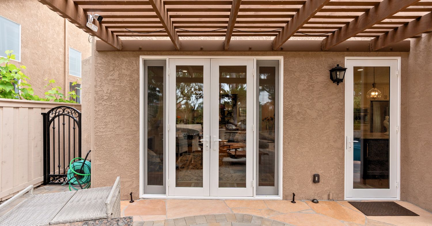 Carmel Valley home remodel — exterior view of newly installed French doors with seamless stucco surround and overhead trellis, by Lars Remodeling & Design
