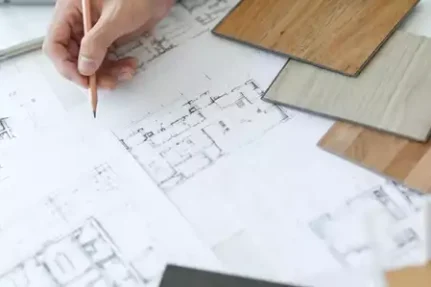 An interior designer looking at floor plans and comparing tile samples.