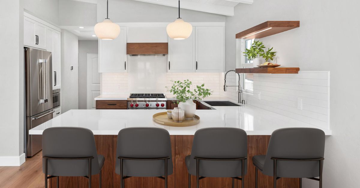 Open-concept aging-in-place kitchen remodel in San Diego featuring a large quartz waterfall island, walnut cabinetry, white shaker cabinets, and accessible circulation space.