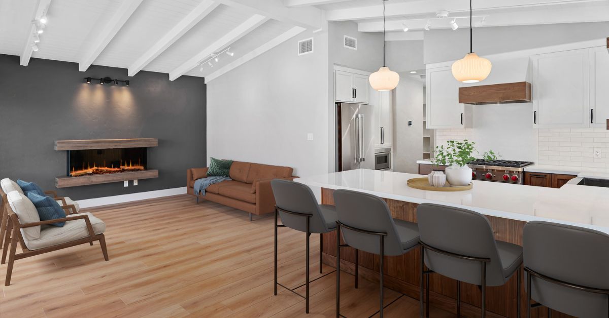 Open-concept kitchen and living room remodel with large island, modern fireplace, and vaulted ceiling in San Diego home.