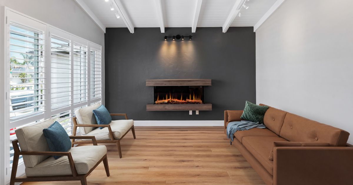 Open-concept living room remodel in San Diego with modern fireplace, vaulted white ceiling, and wide-plank wood flooring designed for brighter aging-in-place living.