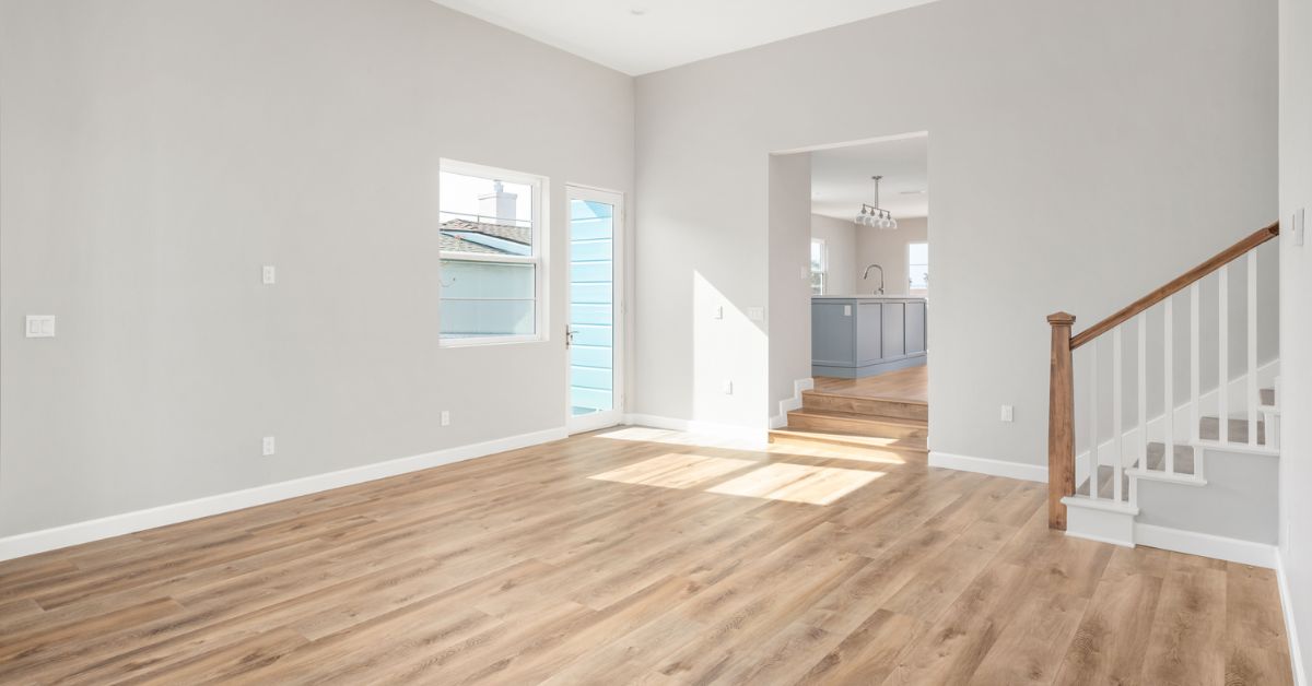 Bright open living room with new staircase and view into kitchen in a Bay Park whole-home remodel and addition by Lars Remodeling & Design.