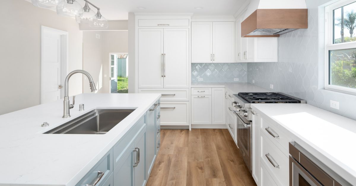 Full kitchen wall with custom white cabinetry, quartz countertops, wood range hood, and designer tile backsplash in a Bay Park whole-home remodel by Lars Remodeling & Design.