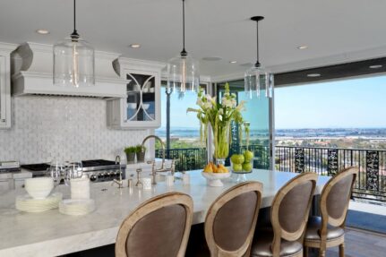 Luxury remodeled kitchen in a San Diego home with integrated indoor-outdoor living, custom cabinetry, marble island, and panoramic views