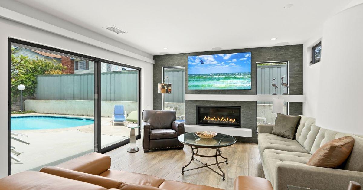Completed luxury living room remodel with large sliding glass doors, modern fireplace, and open indoor-outdoor design.