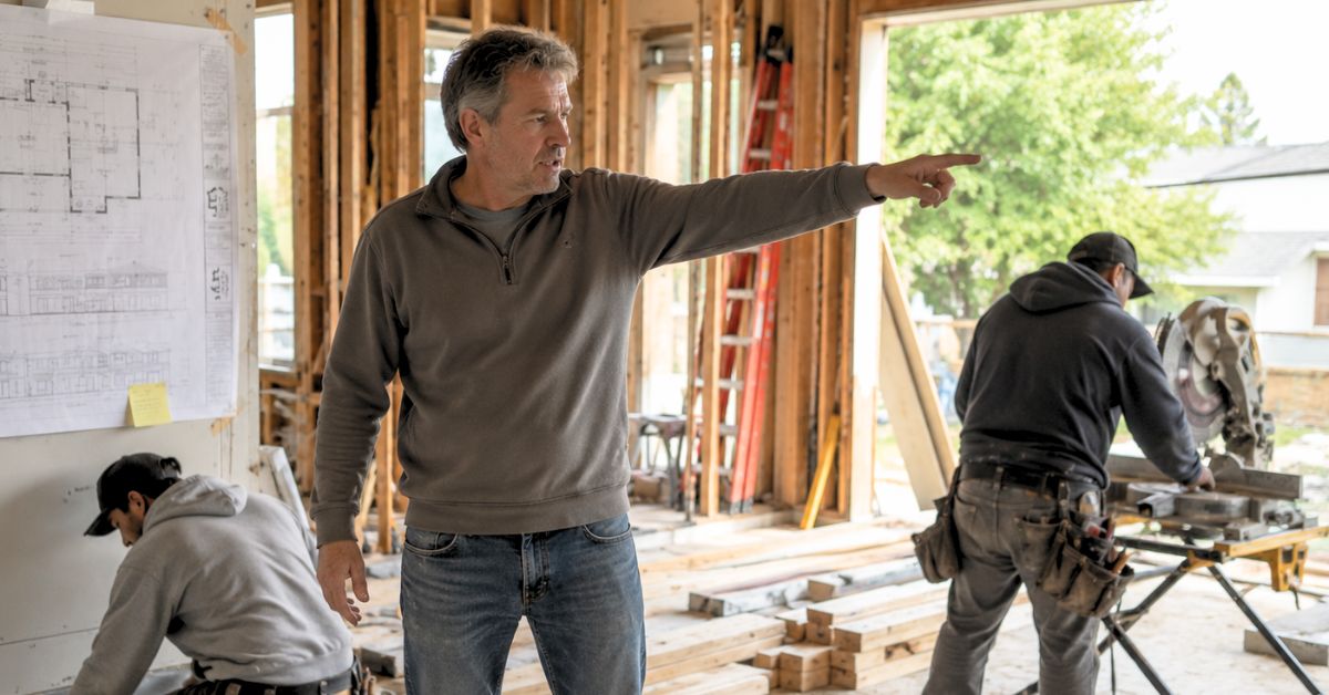 Homeowner directing construction workers during a residential remodeling project inside a partially framed home.