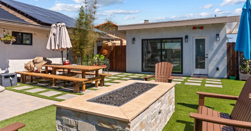 Custom backyard accessory structure in Spring Valley, CA featuring a modern pool house, fire pit, artificial turf, large paver patio, outdoor dining area, and seamless indoor-outdoor living space designed for entertaining and everyday family use.