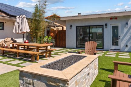 Custom backyard accessory structure in Spring Valley, CA featuring a modern pool house, fire pit, artificial turf, large paver patio, outdoor dining area, and seamless indoor-outdoor living space designed for entertaining and everyday family use.