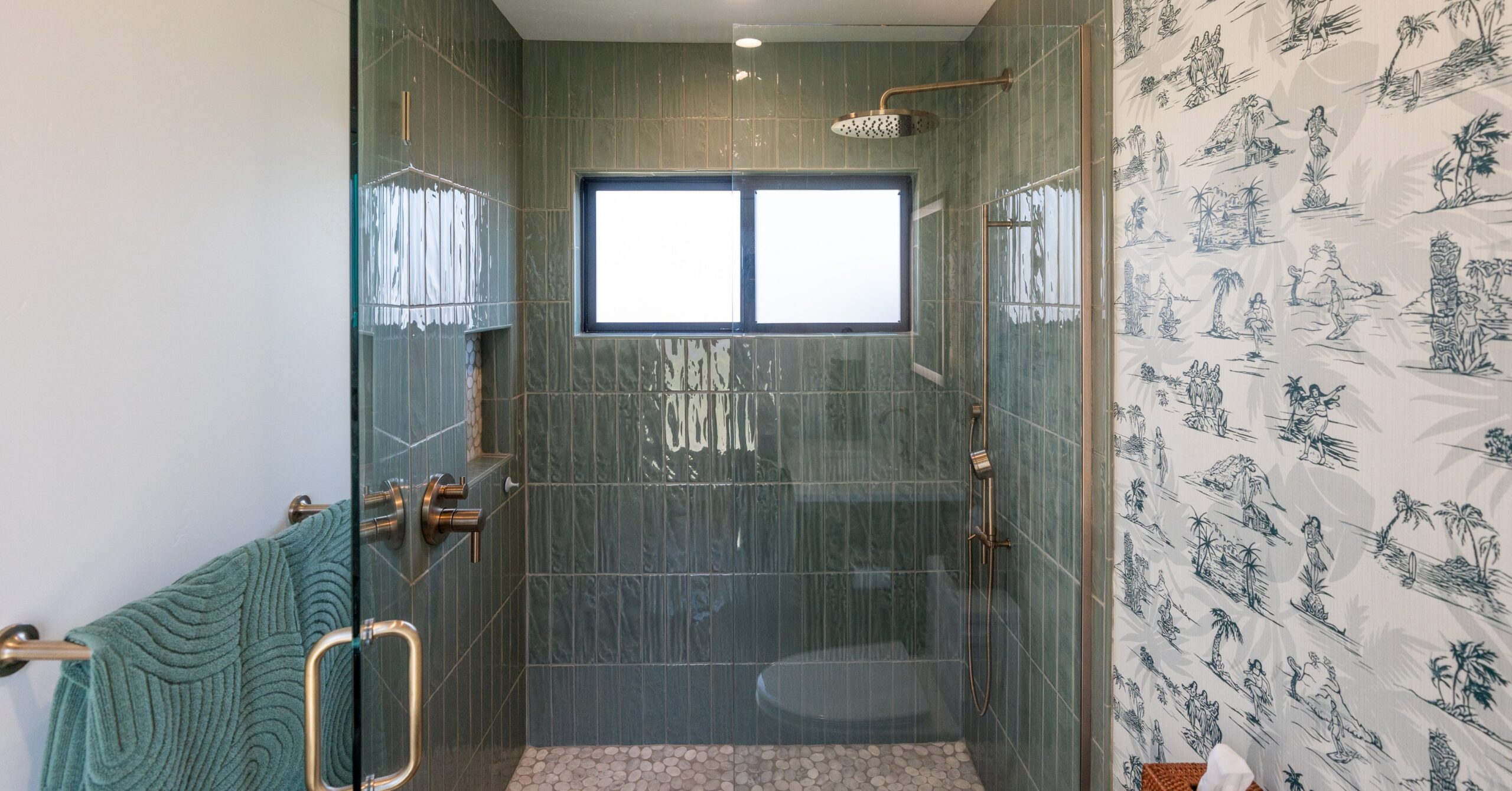 Modern pool bathroom with green tiled walk-in shower, frameless glass enclosure, pebble flooring, and brushed bronze fixtures inside a Spring Valley accessory structure.