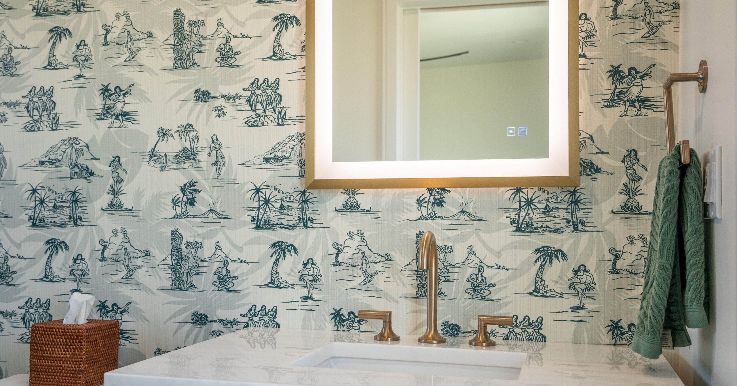 Custom bathroom vanity with wood cabinetry, brass faucet, illuminated mirror, and coastal-inspired wallpaper in a Spring Valley accessory structure.