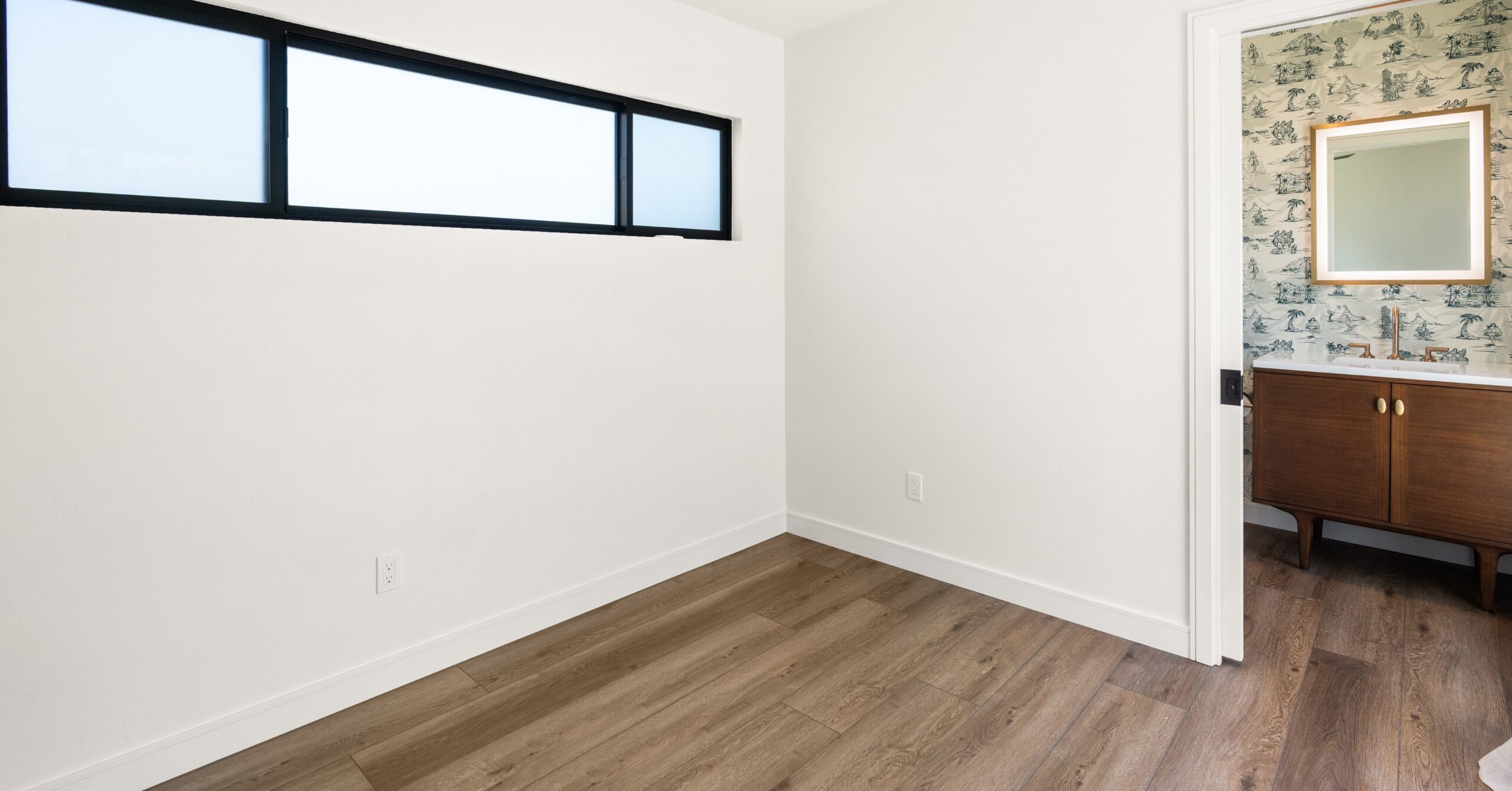 Interior of a newly built backyard accessory structure with luxury vinyl plank flooring, clerestory window, and direct access to a guest bathroom.