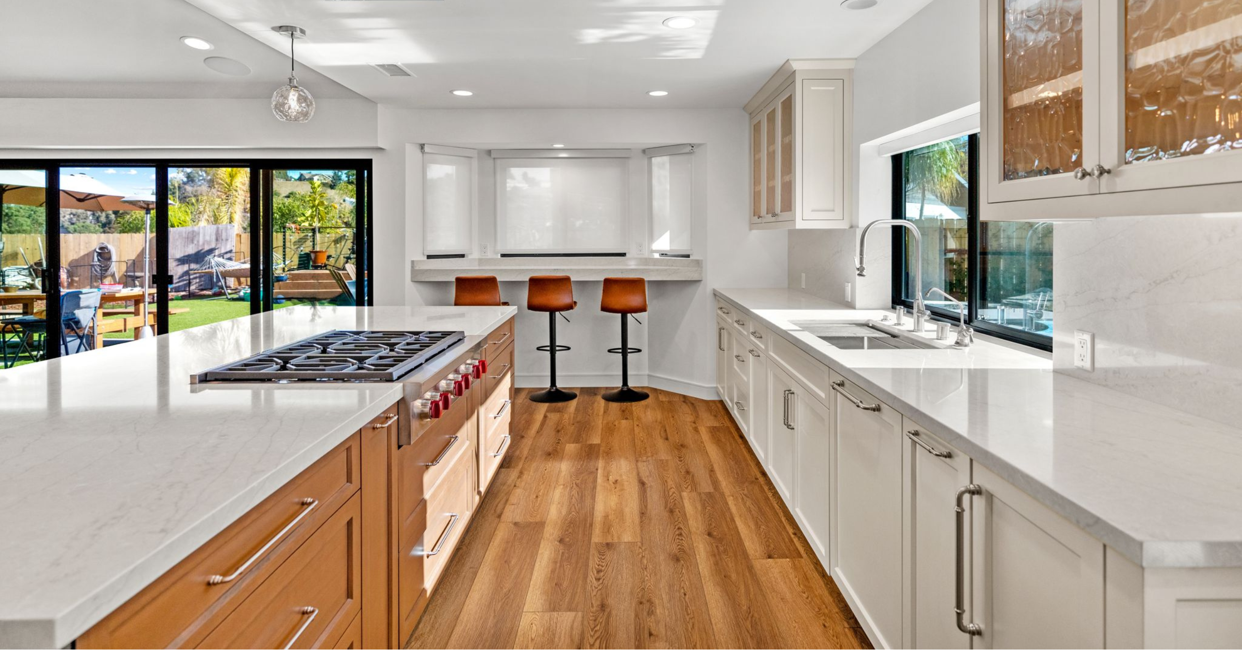 Modern remodeled kitchen with white cabinetry, wood island, stone countertops, and open indoor-outdoor connection.