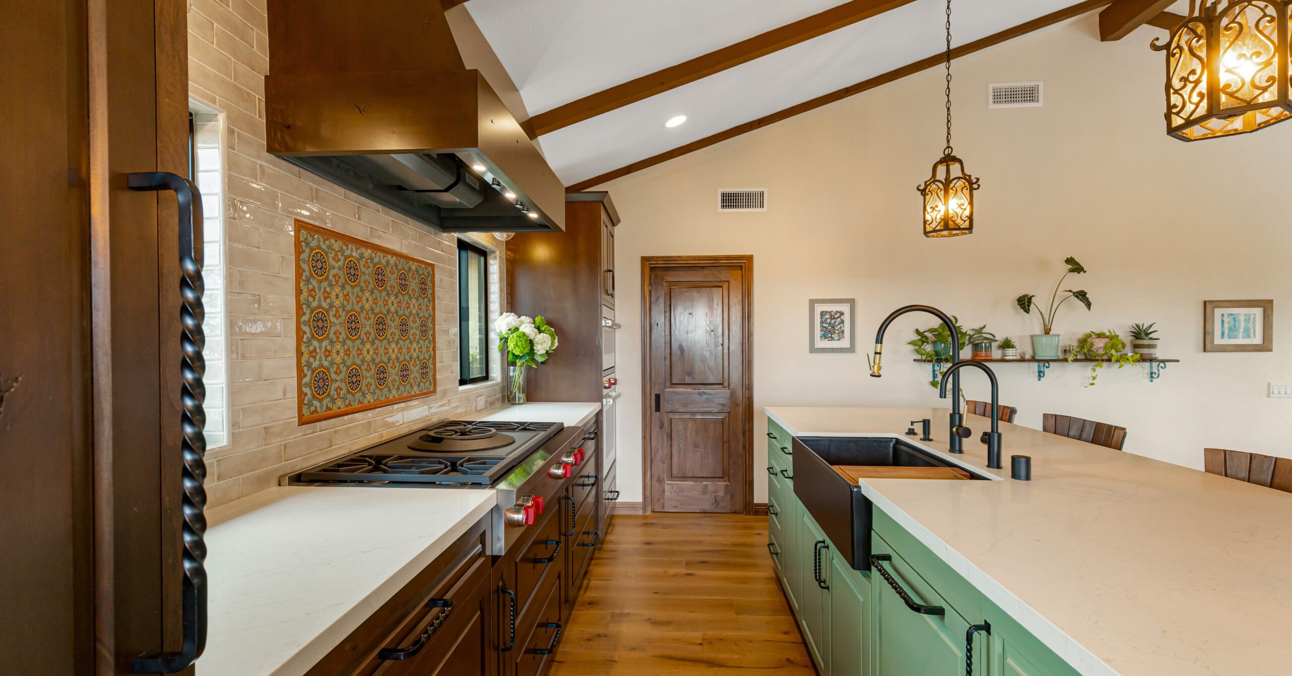 Open-concept kitchen remodel in Vista California with custom wood cabinetry, oversized island, Wolf rangetop, farmhouse sink, exposed ceiling beams, and Spanish-inspired design details.